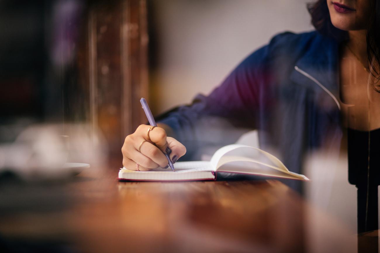 A person writing in a notebook at a table.