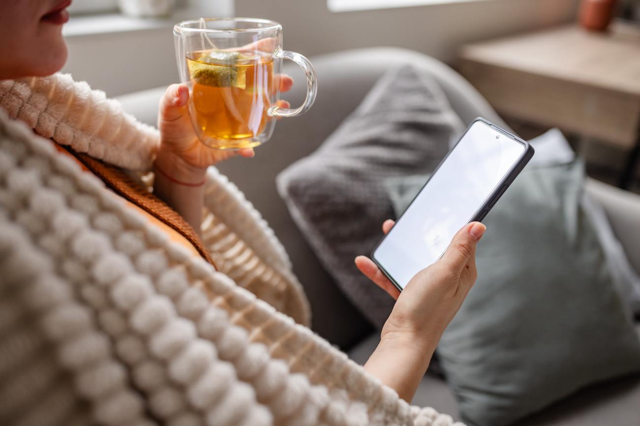A person resting with a warm drink and their phone.