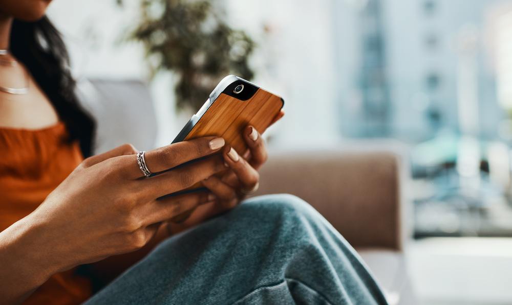 A person holding their phone at home.