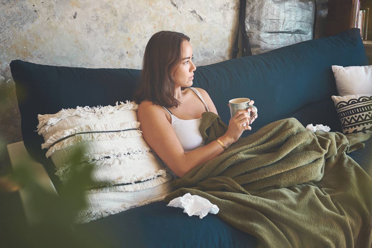 A person resting at home with a warm drink.